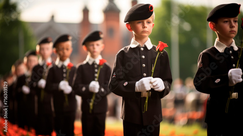 Memorial ceremony with children in military uniforms lined up in a single line and holding red flowers symbolizing remembrance and honor. Memorial Service. Military celebration