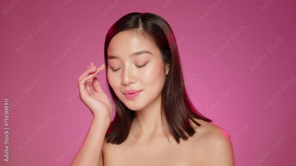 Young Asian model posing against pink background in studio Young Asian model posing against pink background in studio