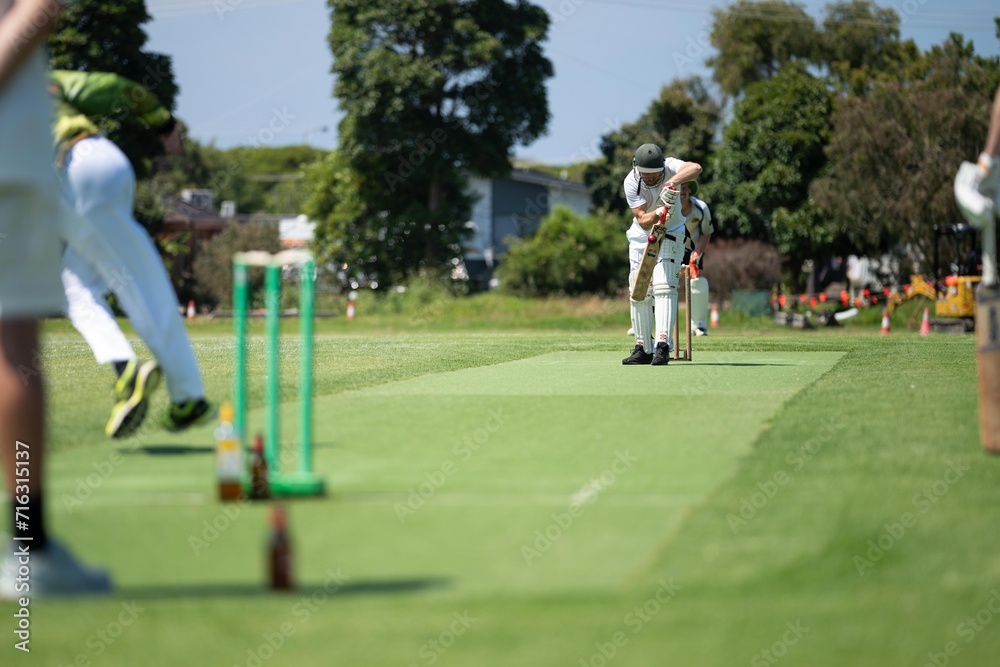 cricketer batting on a cricket pitch, a local cricket match being played on a green cricket oval in summer in australia cricketer batting on a cricket pitch, a local cricket match being played on a green cricket oval in summer in australia