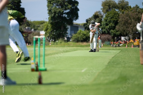 Obraz na płótnie cricketer batting on a cricket pitch, a local cricket match being played on a gr