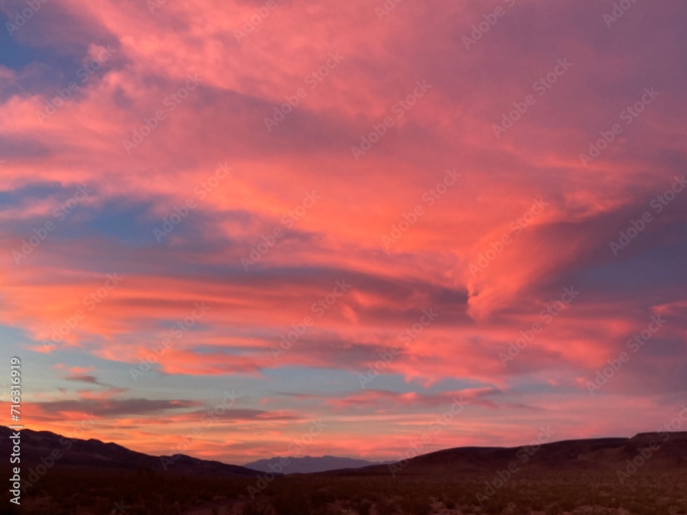 Dark pink clouds over silhouetted mountains at sunset