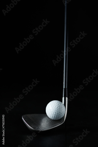 photo of a golf stick with the focus set on the golf ball in front of the stick and with a dark background
