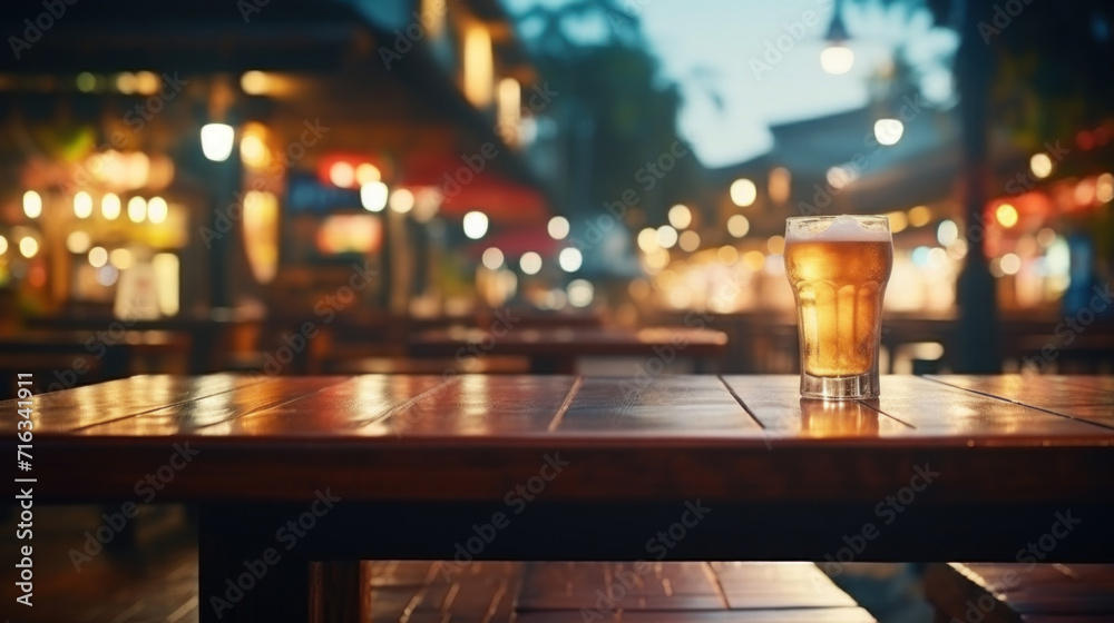 A refreshing glass of beer on a wooden table, set against the lively backdrop of a night-time eatery.