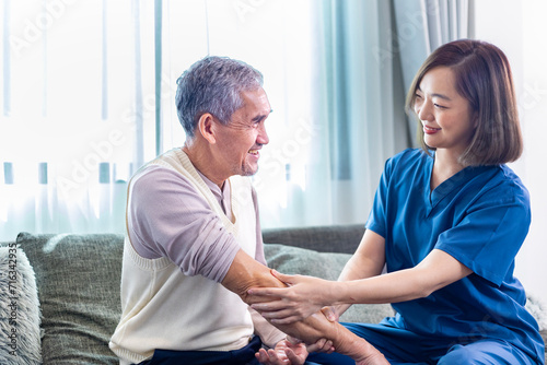 Senior Asian man got medical service visit from caregiver nurse at home while preparing for physical therapy and using ointment rubbing for muscle pain in health care and pension welfare concept photo