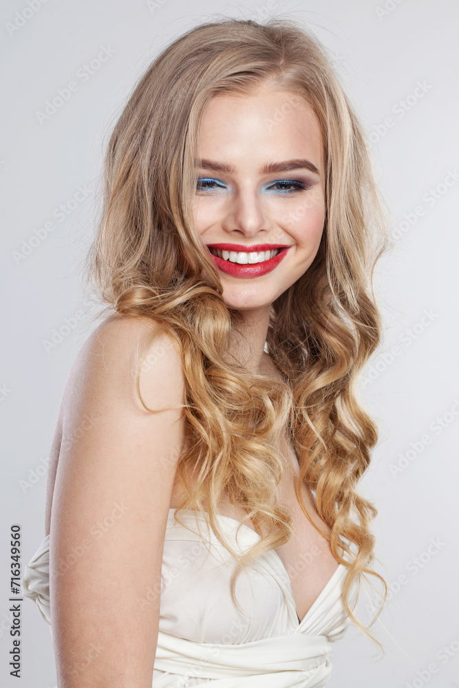 Happy young woman with clean fresh skin and long curly hair looking at camera on white studio wall background, portrait Happy young woman with clean fresh skin and long curly hair looking at camera on white studio wall background, portrait