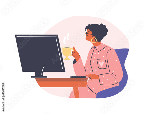 Girl in pajamas with cup of hot drink working at computer.