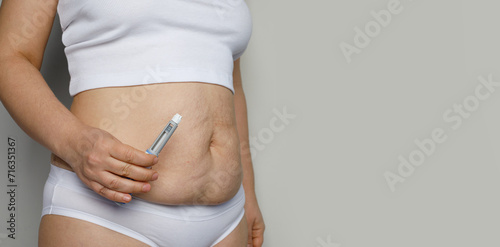 Female body closeup with Semaglutide Injection pen or insulin cartridge pen. Medical equipment for diabetes patient. Diabetes and weight loss concept. photo