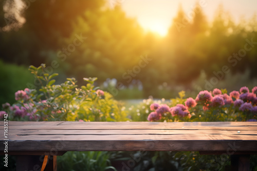 Empty rustic wooden table in front of beautiful flower garden in the sunset with blurry background. Product placement podium.