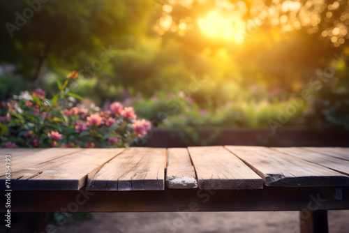 Empty rustic wooden table in front of beautiful flower garden in the sunset with blurry background. Product placement podium.
