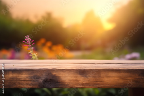 Empty rustic wooden table in front of beautiful flower garden in the sunset with blurry background. Product placement podium.