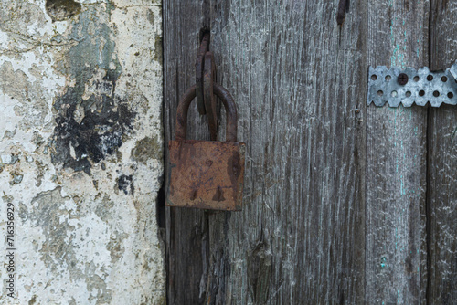 An old padlock on a gray stripped wooden gate. Protect property and privacy. Close-up.