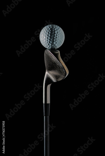 photo of a golf stick with the focus set on the golf ball on the stick and with a dark background