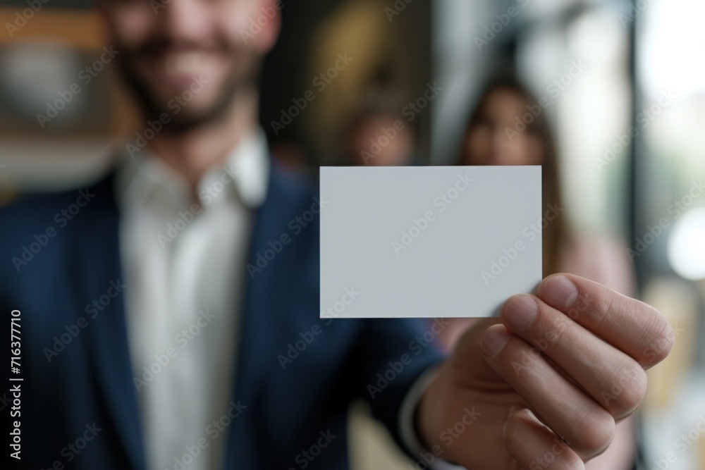 Smiling Businessman Presenting Blank Business Card in Office Environment Smiling Businessman Presenting Blank Business Card in Office Environment