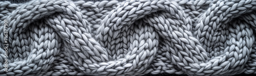 Close-up texture of a gray knitted woolen fabric, depicting the intricacy of the braided pattern