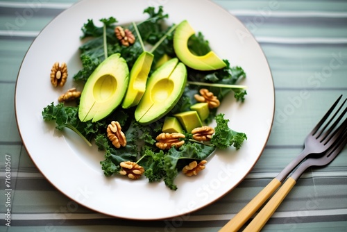 avocado chunks in a kale and walnut salad, metal fork aside