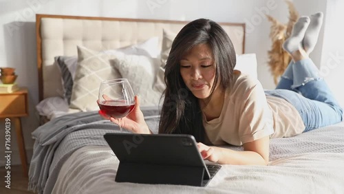 Happy beautiful woman in casual clothes talking on video call on digital tablet lying on the bed. Work from home education online. Playing game shopping online relaxing photo