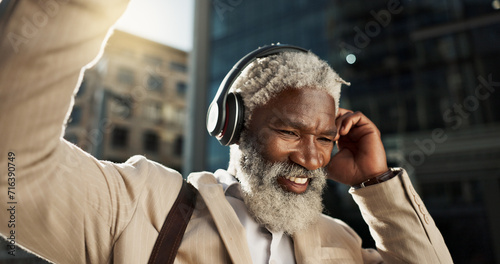 Happy, dancing and senior businessman with headphones in the city walking and listening to music. Smile, happy and elderly African male person streaming playlist, song or radio commuting in town.