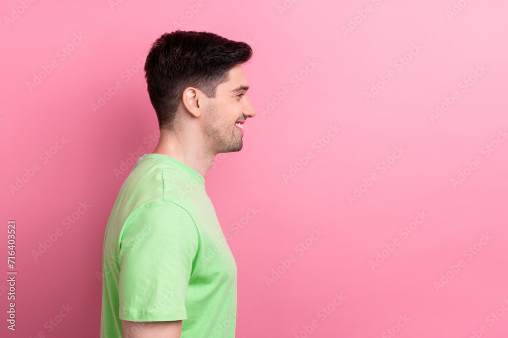 Side profile photo of smiling guy wearing green t shirt look empty space satisfied his handsome appearance isolated on pink color background Side profile photo of smiling guy wearing green t shirt look empty space satisfied his handsome appearance isolated on pink color background