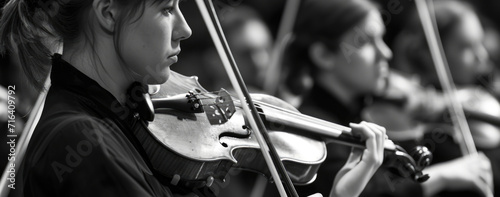 A woman playing a violin in front of a group of people. Perfect for musical performances or events photo