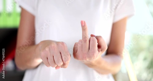 Woman slowly raises middle finger as sign of resentment and contempt hand gesture. Indecent angry gesture and emotions photo