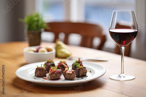 glass of red wine next to a plate of gourmet stuffed mushrooms