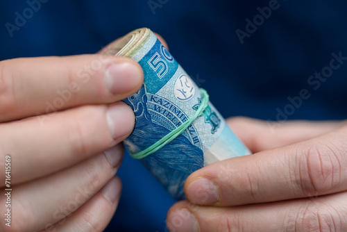 Zwinięty plik banknotów, duże polskie pieniądze w dłoni 