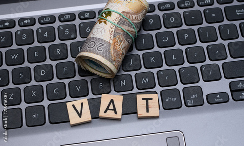 Napis vat z drewnianych klocków leży na laptopie 