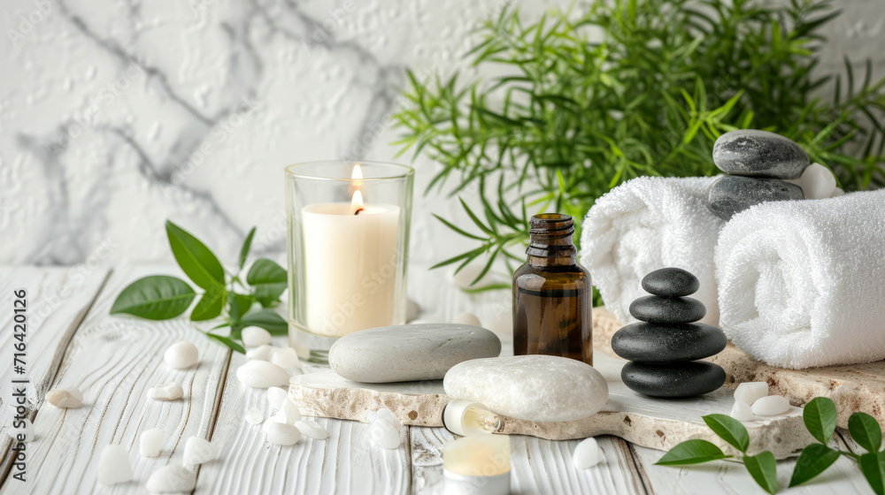 Beauty treatment items for spa procedures on white wooden table and marble wall. massage stones, essential oils and sea salt. candle, rolled up white towel, plants, copy space