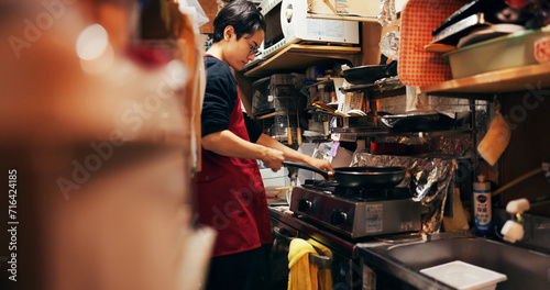 Japanese chef man, stove and pan for cooking, service or catering job with heat, flame and ready. Person, restaurant or cafeteria in kitchen for meal prep, working or thinking with recipe in Tokyo photo