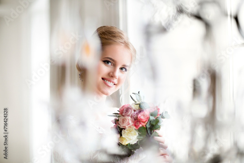 Beautiful blond woman with bouquet posing in a wedding dress