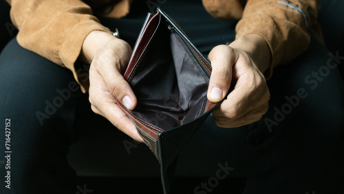 Poor man bankrupt with no credit in debt hand hold empty black leather wallet because economy down turn Empty wallet (no money) in the hands of an man photo