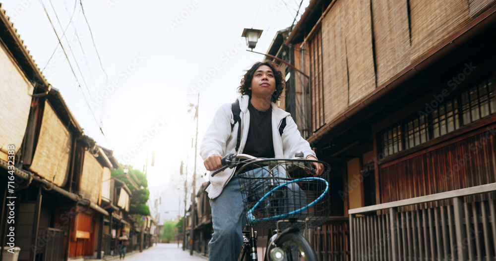 Bike, travel and man riding by building for exercise or transportation to college academy. Fitness, backpack and young male student driving a bicycle to university for carbon footprint by houses. Bike, travel and man riding by building for exercise or transportation to college academy. Fitness, backpack and young male student driving a bicycle to university for carbon footprint by houses.