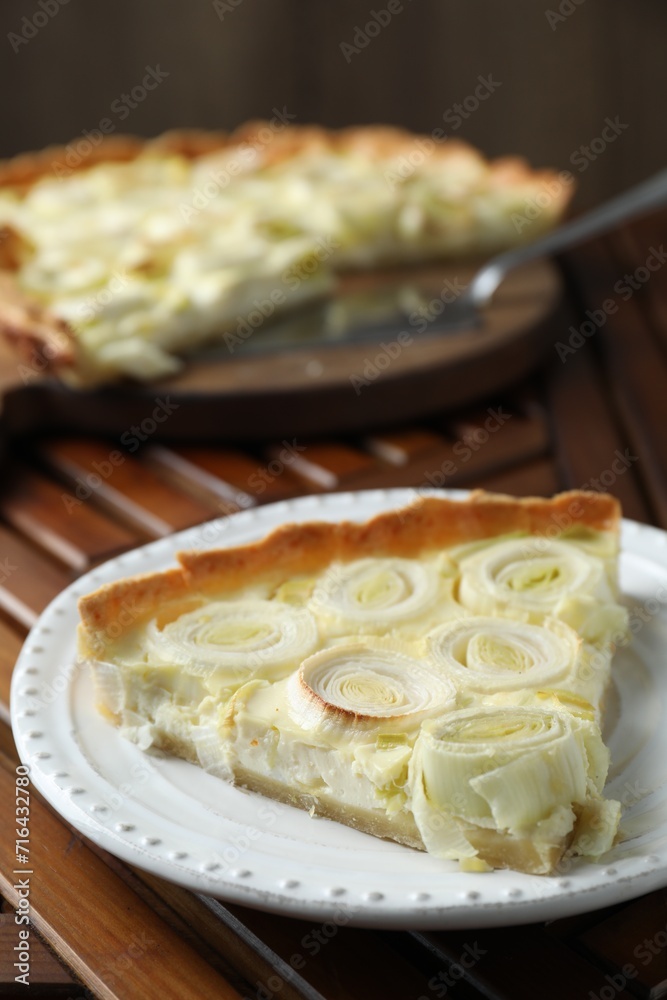 Plate with piece of tasty leek pie on wooden table, closeup Plate with piece of tasty leek pie on wooden table, closeup