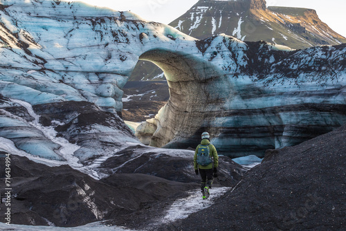 A guy standing in front of the arch of Katla Glacier in Iceland