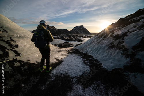 A guy climbing at katla glacier in iceland with sun in background photo