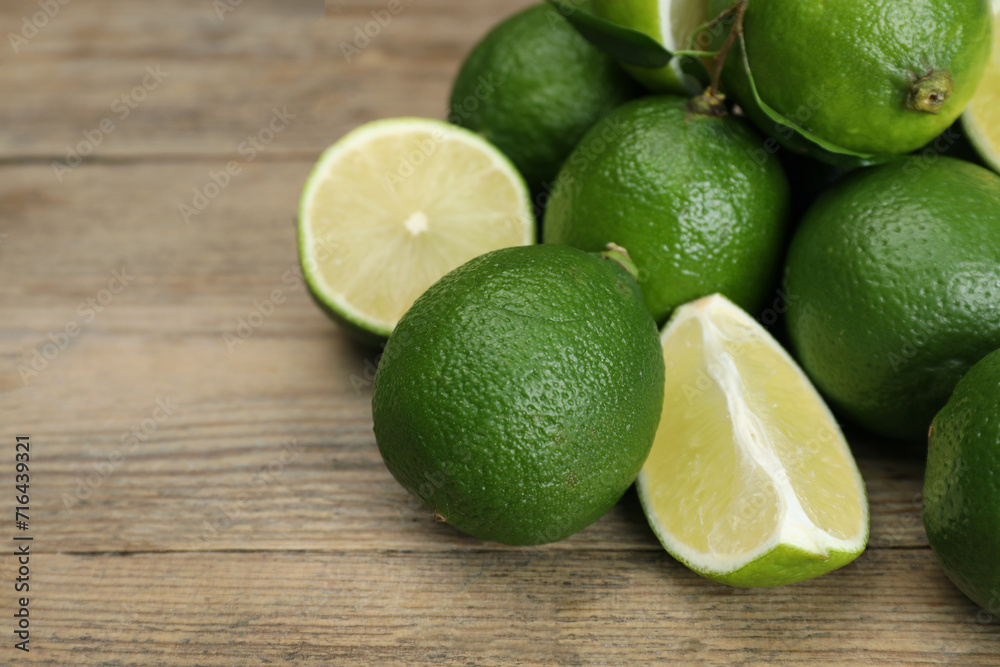 Pile of fresh limes on wooden table, closeup. Space for text Pile of fresh limes on wooden table, closeup. Space for text