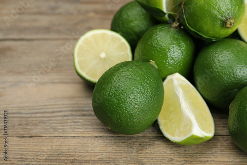 Pile of fresh limes on wooden table  closeup. Space for text