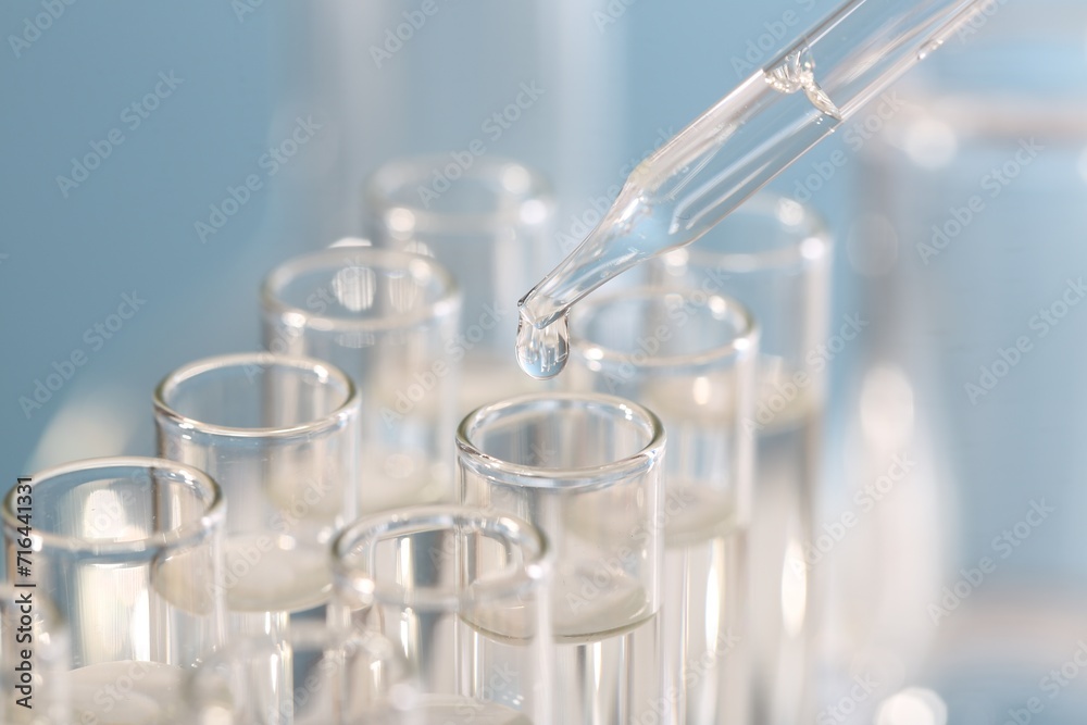 Laboratory analysis. Dripping liquid from pipette into glass test tube on blurred background, closeup Laboratory analysis. Dripping liquid from pipette into glass test tube on blurred background, closeup