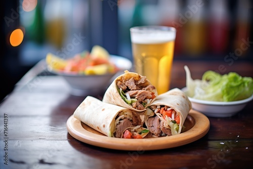 shawarma wraps in foil on a rustic table with cold drinks aside photo