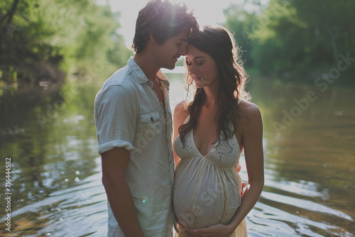 Young pregnant woman with partner in river at spring countryside