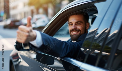 Side view of businessman in suit driving expensice car, smiling happily and showing thumb up, closeup. Young man entrepreneur going home by car after successful business meeting.