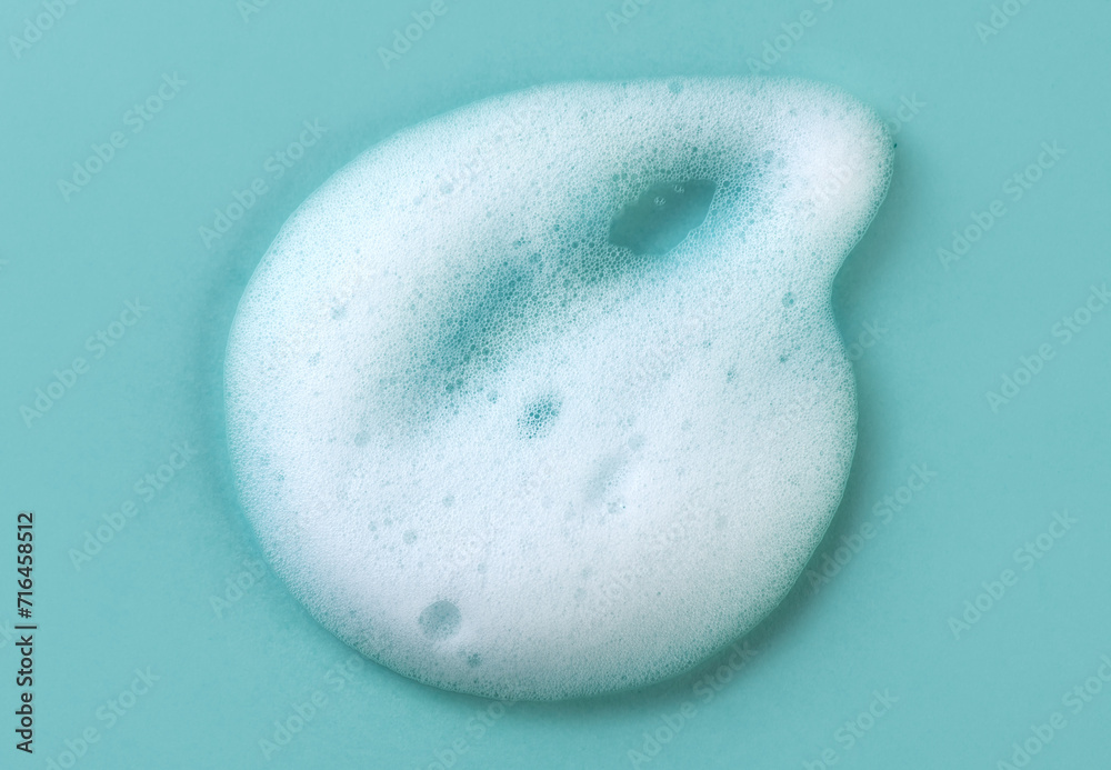 Foam smudge on blue background. Liquid soap bubbles, Froth bubbles backdrop. Cosmetics soap foam popping bubble. Soap sud macro structure close-up. Clean, cleaning, washing, laundry. Top view
