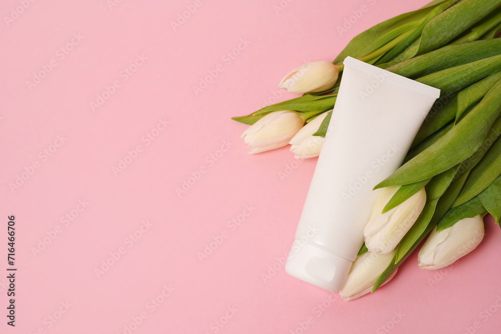 White tube with cosmetic cream or lotion for body and bouquet of white tulips, pink background, copy space White tube with cosmetic cream or lotion for body and bouquet of white tulips, pink background, copy space