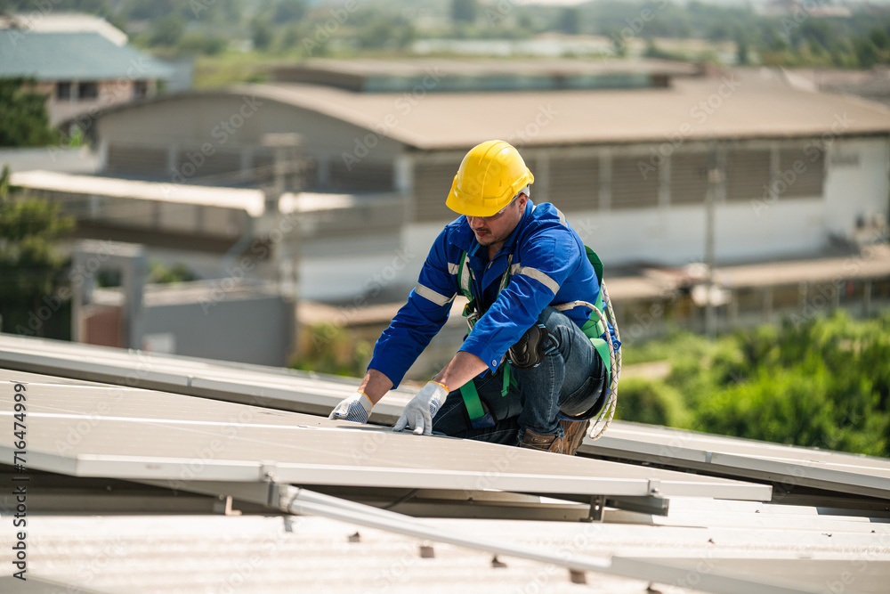 Men technicians carrying photovoltaic solar modules on the factory roof. Engineers in helmets installing solar panel systems outdoors. Concept of alternative and renewable energy solar cell. Men technicians carrying photovoltaic solar modules on the factory roof. Engineers in helmets installing solar panel systems outdoors. Concept of alternative and renewable energy solar cell.