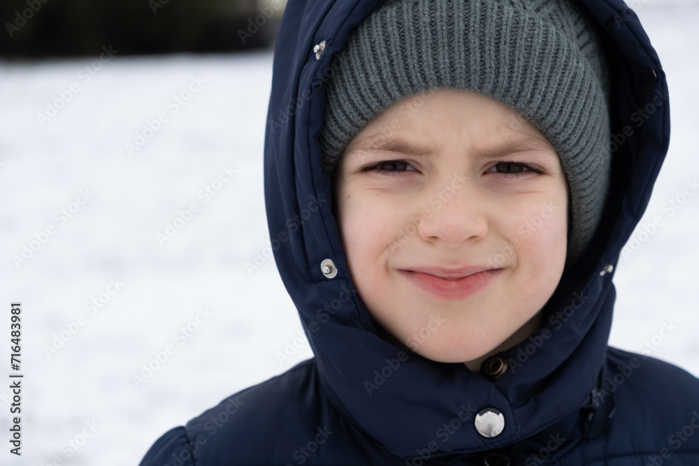 Six-year-old boy in warm winter clothes hat and jacket, close-up portrait. Six-year-old boy in warm winter clothes hat and jacket, close-up portrait.