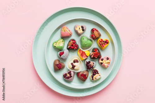 Plate with different chocolate on colored background. Assortment of fine chocolates top view vith copy space Health and obesity concept