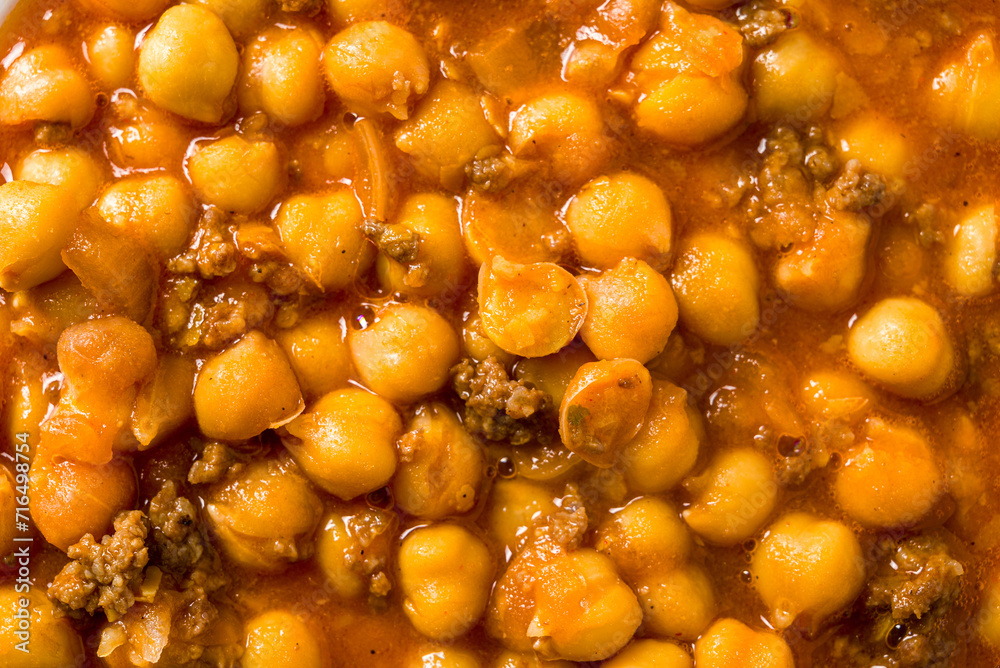 Chickpea stew with minced meat on a white porcelain plate on a stone table Chickpea stew with minced meat on a white porcelain plate on a stone table