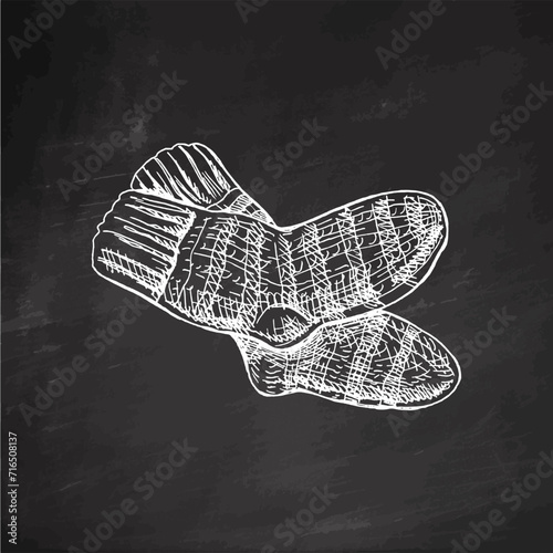 Hand-drawn sketch of knitted socks on chalkboard background. Knitwear, handmade concept in vintage doodle style. Engraving style.	