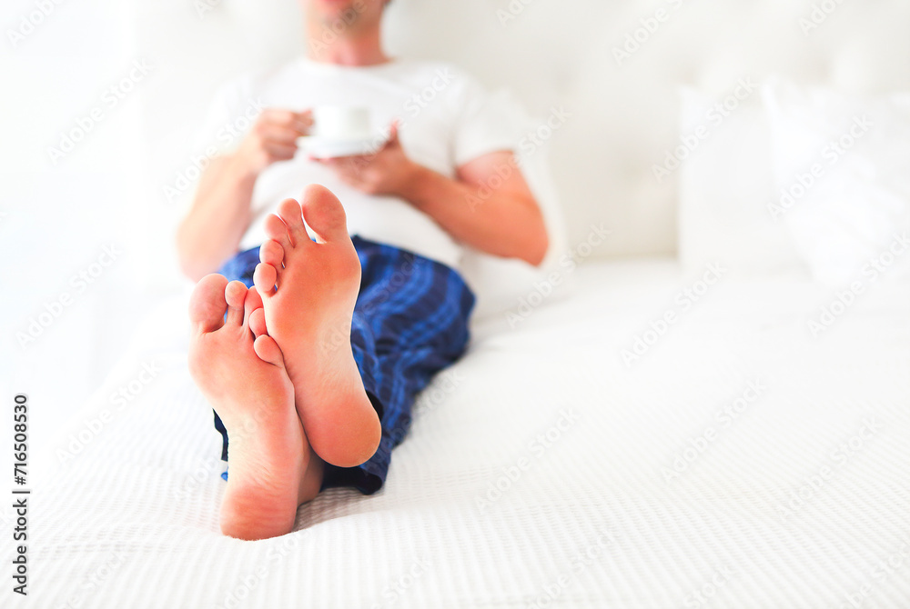 Naklejka premium Young man drinking morning coffee in the bed