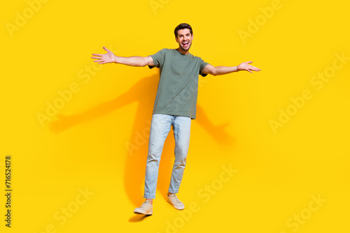 Full length photo of cheerful positive man dressed khaki t-shirt open arms missing you isolated yellow color background